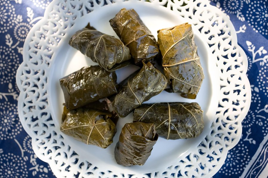 Dolmathes, stuffed grape leaves on a white lace-edged plate