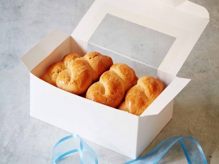 A white gift box of assorted Greek cookies tied with a blue ribbon