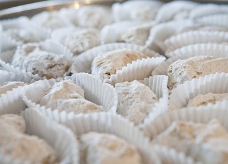 Kourambiethes, powdered-sugar butter cookies in paper cups on a tray