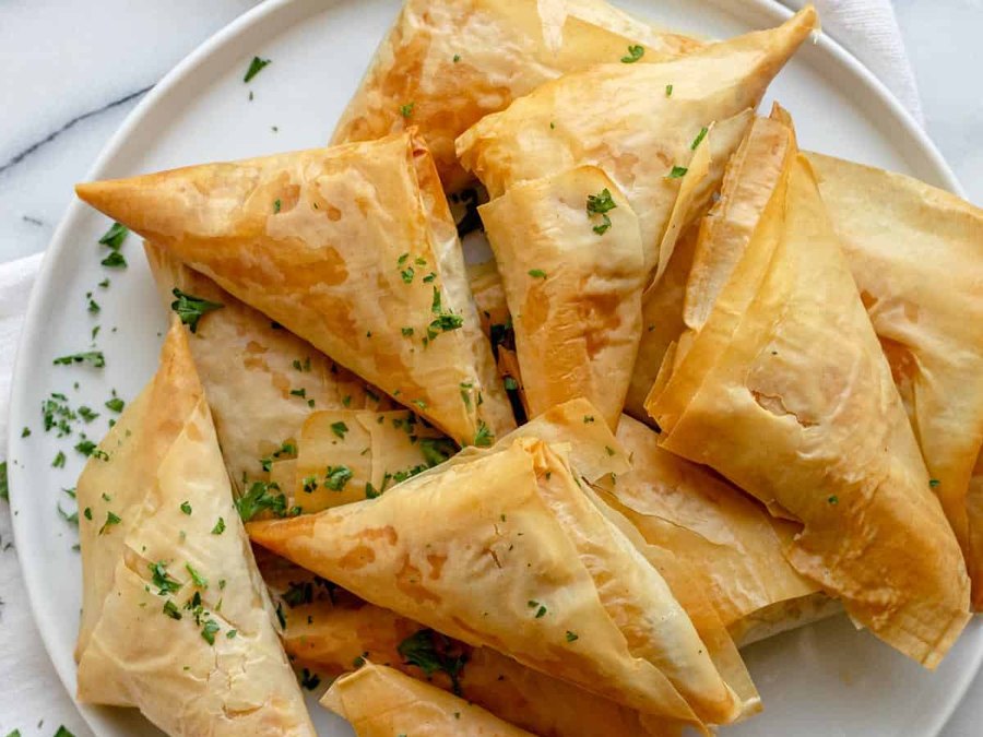 Spanakopita, golden spinach and cheese phyllo triangles sprinkled with parsley