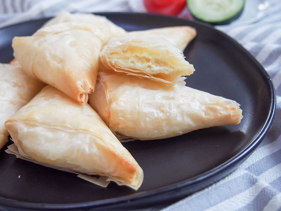 Tiropita, triangles of cheese-filled phyllo pastry on a dark plate